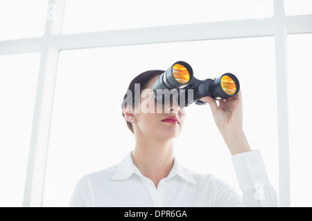 Geschäftsfrau, Blick durch ein Fernglas im Büro Stockfoto