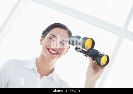 Lächelnde Business-Frau mit dem Fernglas im Büro Stockfoto