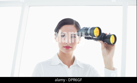 Ernsthafte Business-Frau mit dem Fernglas im Büro Stockfoto