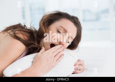 Frau mit geschlossenen Augen in Bett Gähnen Stockfoto