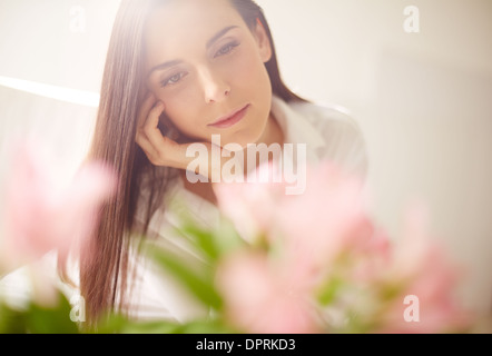 Porträt von reizenden Dame Blick auf Blumen Stockfoto