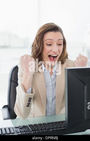 Elegante Geschäftsfrau jubeln am Schreibtisch Stockfoto