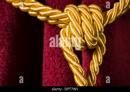 Roter Samtvorhang mit Quaste. Knoten im Seil hautnah Stockfoto