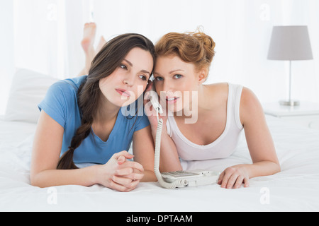 Schöne Frau mit Freund mit Telefon im Bett Stockfoto