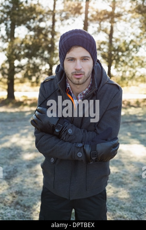 Mann in warme Kleidung Zittern beim Spazierengehen im Wald Stockfoto