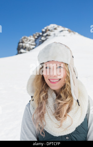 Lächelnde Frau vor verschneiten Hügel und klaren, blauen Himmel Stockfoto