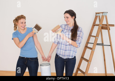 Freunde mit Pinsel und können in einem neuen Haus Stockfoto