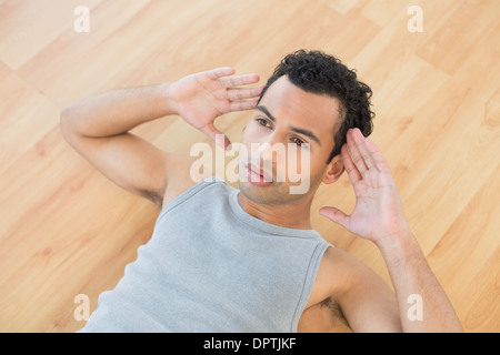 Junge Mann tut Bauch-Crunches auf Parkett Stockfoto