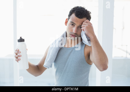 Junger Mann wischte sich Schweiß mit Handtuch im Fitness-studio Stockfoto