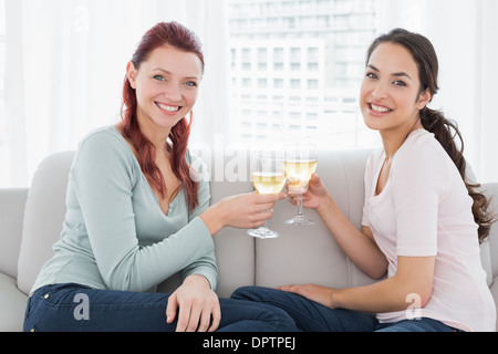 Zwei glückliche junge Freundinnen Toasten Weingläser zu Hause Stockfoto