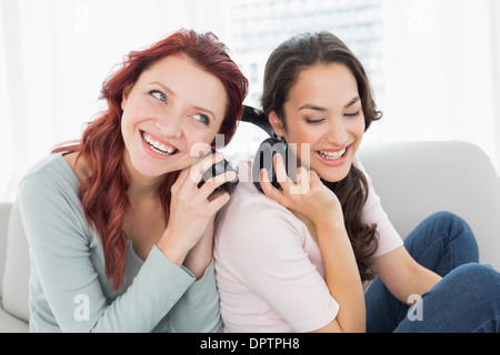 Freunden zusammen Musik über Kopfhörer zu hören, die zu Hause Stockfoto