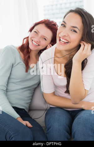 Freunden zusammen Musik über Kopfhörer zu hören, die zu Hause Stockfoto