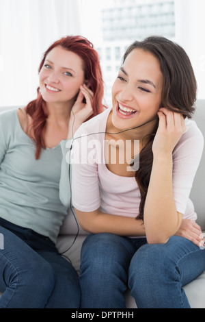 Freunden zusammen Musik über Kopfhörer zu hören, die zu Hause Stockfoto