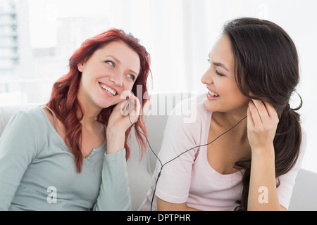 Freunden zusammen Musik über Kopfhörer zu hören, die zu Hause Stockfoto