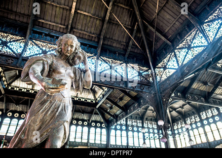 SANTIAGO, Chile – Eine dekorative Statue, die eine Frau mit Wasser zeigt, steht im Zentrum des historischen Mercado Central. Die kunstvollen schmiedeeisernen architektonischen Details des Gebäudes aus dem 19. Jahrhundert bilden den Rahmen für die Skulptur und zeigen das viktorianische Industriedesign des Marktes. Die Statue dient als zentraler Anlaufpunkt auf Chiles wichtigstem Meeresfrüchtemarkt. Stockfoto