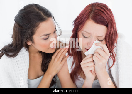 Junge Frau, die eine weinende Freundin trösten Stockfoto