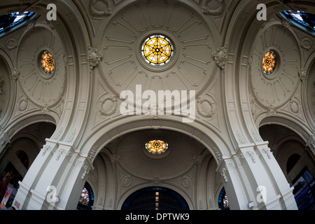 Estacion Mapocho Dome Buntglas Santiago Chile // SANTIAGO, Chile — das reich verzierte Kuppeldach des Estacion Mapocho verfügt über exquisite Buntglaselemente, die die architektonische Pracht und historische Bedeutung des Gebäudes demonstrieren. Der 1912 erbaute ehemalige Bahnhof diente als Hauptverkehrsknotenpunkt von Santiago, bevor er in ein Kulturzentrum umgewandelt wurde. Die akribisch restaurierte Kuppel ist ein Beispiel für den Beaux-Arts-Architekturstil, der während der chilenischen Entwicklung des frühen 20. Jahrhunderts beliebt war. Heute fungiert Estacion Mapocho als prominenter öffentlicher Tagungs- und Konzertsaal Stockfoto