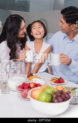 Fröhliches junges Mädchen genießen das Frühstück mit den Eltern Stockfoto