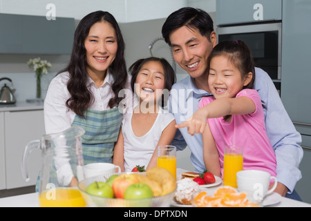 Fröhliche vierköpfige Familie genießen gesundes Frühstück in der Küche Stockfoto