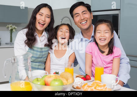 Fröhliche vierköpfige Familie genießen gesundes Frühstück in der Küche Stockfoto