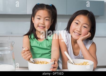 Porträt von zwei lächelnde Mädchen sitzen mit Schalen in Küche Stockfoto