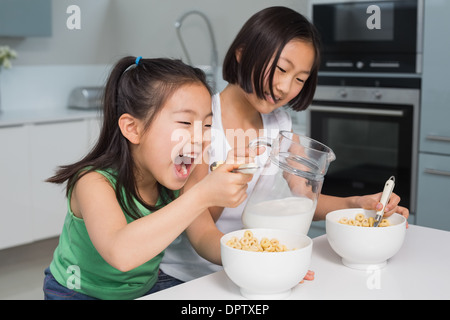 Zwei glückliche junge Mädchen essen Getreide in Küche Stockfoto