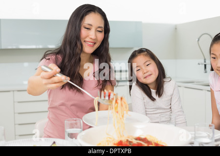 Mädchen beobachten glückliche Frau dienen Spaghetti in Küche Stockfoto