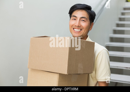 Lächelnde junge Mann trägt Boxen gegen Treppe Stockfoto
