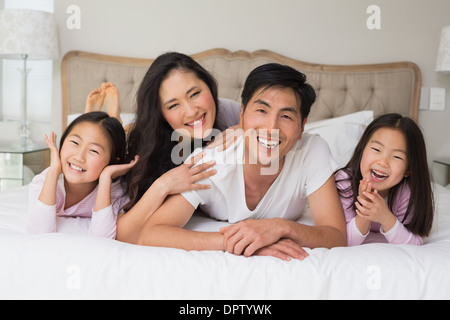 Fröhliche Familie von vier im Bett liegend Stockfoto