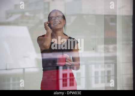 Chinesische Frauen betrachten auf smart Phone in Fenster Stockfoto