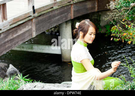 Junge Frau in traditioneller Wear Picking Branch Stockfoto