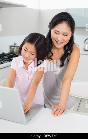 Lächelnde Mutter mit Tochter mit Laptop in der Küche Stockfoto