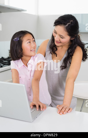 Lächelnde Mutter mit Tochter mit Laptop in der Küche Stockfoto