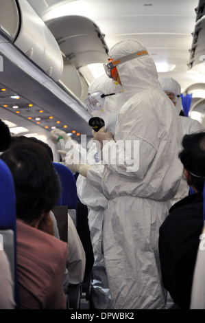 Männer in weißen Schutz Anzüge Überprüfung Flugpassagieren für Fieber und H1N1-Grippe-Symptome vor der Ankunft in Shanghai China Stockfoto