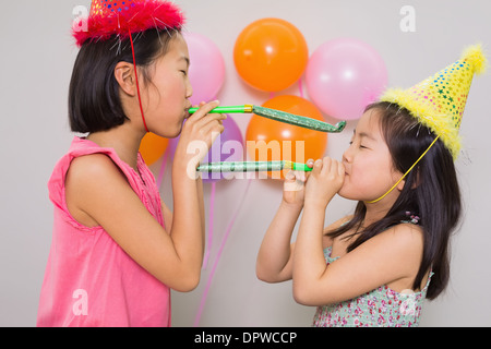 Mädchen bläst Krachmacher auf einer Geburtstagsfeier Stockfoto