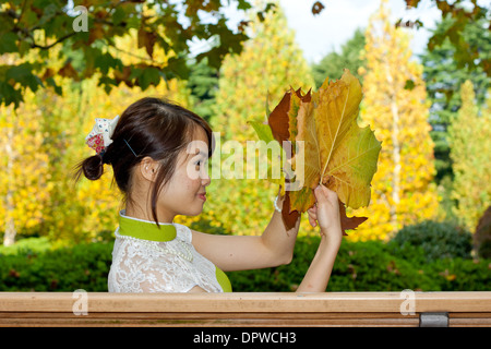 Junge Frau mit großen Blätter im Herbst Stockfoto