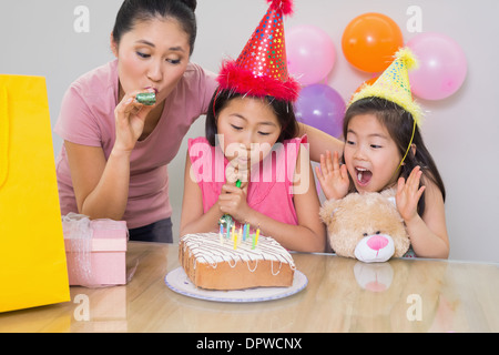 Mädchen und Mutter bläst Krachmacher auf einer Geburtstagsfeier Stockfoto