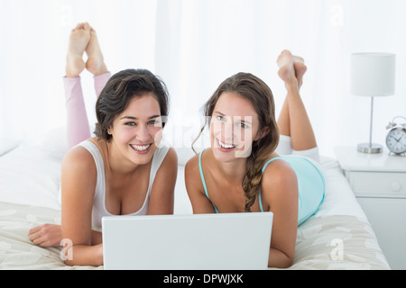 Glücklich entspannt Freundinnen mit Laptop im Bett Stockfoto