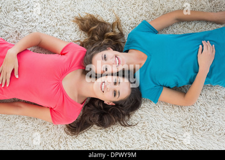 Porträt von zwei jungen Freundinnen auf Teppich liegend Stockfoto