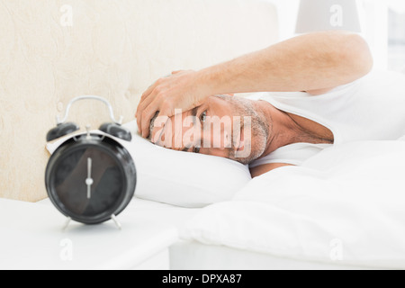 Menschen, die Ruhe im Bett mit Wecker im Vordergrund Stockfoto