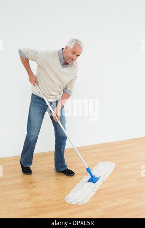 Voller Länge Porträt eines lächelnden Reifen den Boden wischen Stockfoto