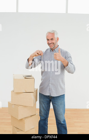 Mann mit Boxen und Schlüssel gestikulieren Daumen nach oben in ein neues Haus Stockfoto