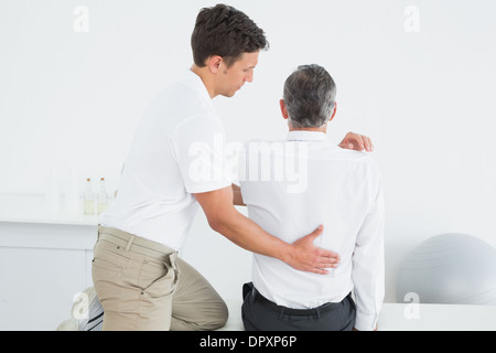 Ansicht von hinten von einem Chiropraktiker untersuchen Mann Stockfoto