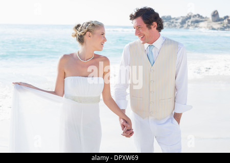 Brautpaar hand in hand gehen und sich gegenseitig lächelnd Stockfoto
