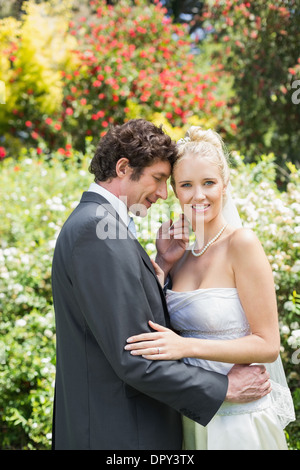 Romantische lächelnden Brautpaar umfassenden Blick in die Kamera Stockfoto