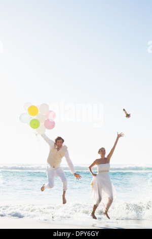 Bräutigam Holding Ballons und Braut werfen ihren Blumenstrauß springen Stockfoto