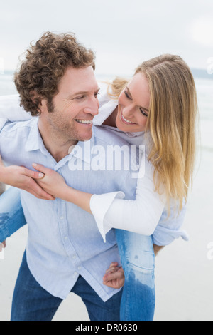Mann Huckepack Frau am Strand Stockfoto