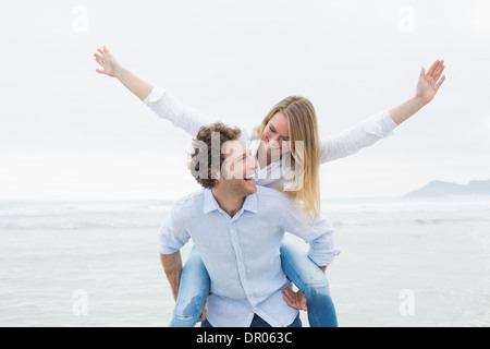 Mann Huckepack Frau am Strand Stockfoto