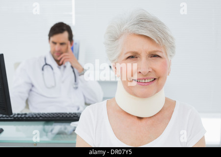 Ältere Patienten in chirurgischen Kragen mit Arzt im Büro Stockfoto