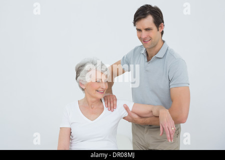 Physiotherapeuten massieren eine lächelnde senior Frau arm Stockfoto